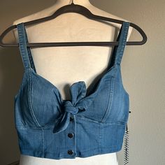 Trendy Denim Sleeveless Crop Top By Haute Monde Features A Built In Padded Chest And Thick Shoulder Straps. This Top Has Lots Of Stretch And There Is A Front Closure That Includes A Tie And 3 Snap Buttons. This Cute Crop Is Very Versatile! You Can Dress It Up Or Down, Layer It, And It Also Pairs Well With Other Denim * Please Note There Is A Flaw Shown In The Last Photo - The Back Piece Of The Middle Snap Button Is Missing. Super Easy Fix And The Button Replacement Can Be Found At Walmart For $1 Casual Denim Blue Vest Top, Dark Wash Denim Sleeveless Tank Top, Dark Wash Denim Tank Top, Trendy Blue Denim Vest Top, Casual Medium Wash Denim Tank Top, Dark Wash Vest Top For Summer, Summer Dark Wash Denim Vest For Day Out, Fitted Sleeveless Crop Top In Medium Wash, Spring Cotton Denim Vest Top