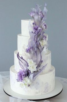 a three tiered wedding cake with purple and white flowers