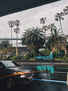 there is a car that is parked in front of a building with palm trees behind it