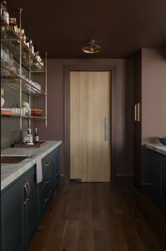 an empty kitchen with wooden floors and blue cabinets, along with shelves on the wall