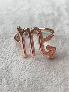 a gold ring with the letter m on it sitting on a white surface in front of a pile of carpet