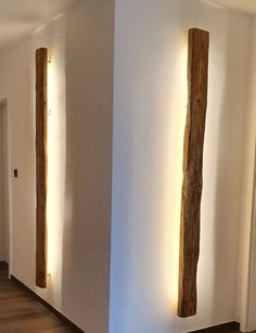 two wooden poles are next to each other in a room with white walls and wood flooring