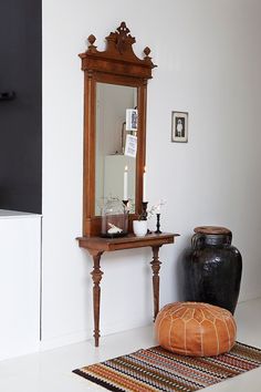 a small table with a mirror and vase on it