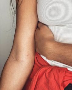 a pregnant woman's arm and belly with her hand on the stomach, while she is wearing a white top