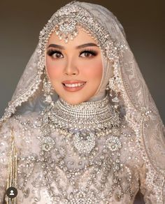 a woman in a white wedding dress and veil with pearls on her head, wearing a tiara