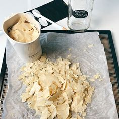 a table topped with lots of food next to a cup filled with liquid and spoons