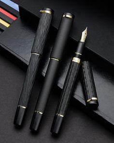 three different types of fountain pens sitting on top of a black table next to each other