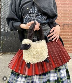 a woman in a kilt holding a sheep purse