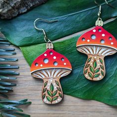 the earrings are made out of wood and painted with red, orange and green mushrooms