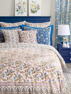 a bed in a bedroom with blue headboard and pillows on top of the bedspread