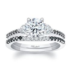 a diamond engagement ring with black and white diamonds on the band, set in 18k white gold