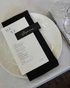 a white plate topped with a menu on top of a table next to silverware