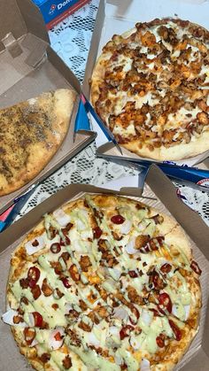 three different pizzas in boxes on a table