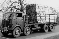 an old black and white photo of a truck carrying lumber