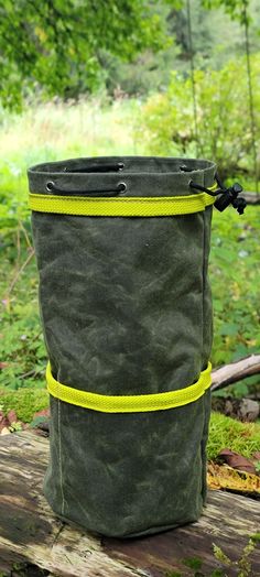 a large green bag sitting on top of a wooden bench in the woods with yellow straps