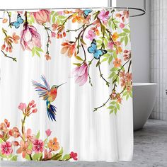 a shower curtain with colorful flowers and a hummingbird on it's side, in front of a bathtub