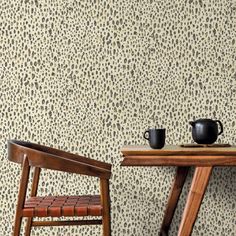 two wooden chairs sitting next to each other near a table and wall with leopard print on it