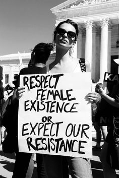 a woman holding a protest sign in front of the supreme court