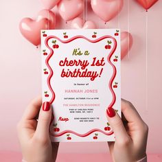 a person holding up a birthday card in front of some heart - shaped balloons with the words it's a cherry 1st birthday