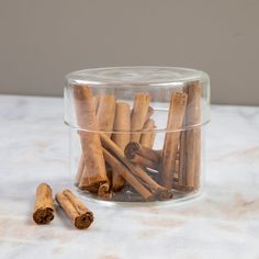 cinnamon sticks in a glass container on a marble counter