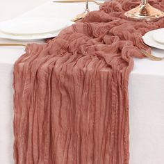 the table is set with white plates and silverware, along with a pink blanket draped over it