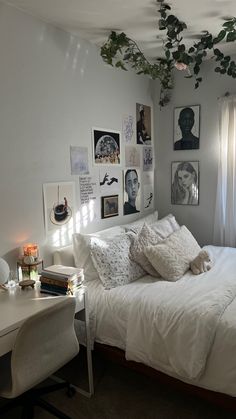 a white bed sitting in a bedroom next to a desk and window with pictures on the wall