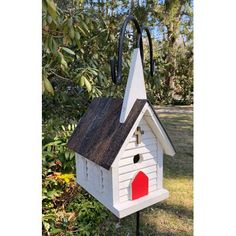 a white birdhouse with a red door and black roof