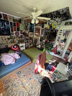 a messy bedroom with lots of clutter and pictures on the wall above the bed