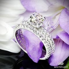 a diamond ring sitting on top of a purple flower next to a white and purple flower