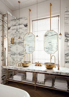 a bathroom with marble counter tops and gold fixtures on the wall, along with two sinks