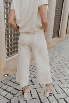 The go-to for laid-back elegance: our Willow Cream Woven Cropped Pants. Imbued with a breezy sophistication, these pants effortlessly blend comfort with style, making them a wardrobe staple for any modern fashionista. Crafted with a Cream and White Woven Design, these pants exude an air of refinement with a subtle yet captivating visual texture. The Cropped Wide Pant Legs offer a relaxed silhouette that drapes beautifully, adding an element of effortless chic to any ensemble. Designed for both f Chic Wide-leg Culottes For Day Out, Versatile Cropped Leg Loungewear Bottoms, Spring Cropped Leg Bottoms For Day Out, Relaxed Fit Cropped Capris For Day Out, Spring Bottoms With Cropped Legs For Day Out, Versatile Spring Capris With Elastic Waistband, Relaxed Fit Cropped Leg Capris For Day Out, Chic Beige Wide-leg Culottes, Chic Cropped Wide Leg Pants With Relaxed Fit