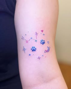 a small tattoo on the arm of a woman with stars and hearts in blue ink