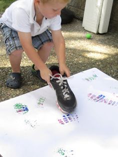 a young boy is playing with a shoe on a white table outside in the sun