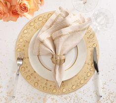 a place setting with napkins, silverware and rose petals on the tablecloth