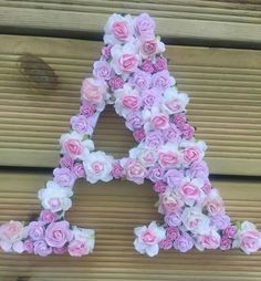 pink and white flowers are arranged in the shape of a letter on a wooden surface