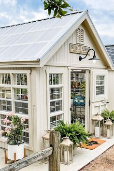 a small white building with potted plants in the front and windows on the side