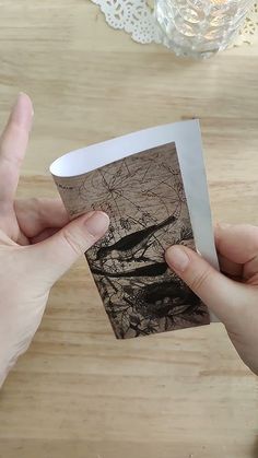 two hands holding an old photo on a wooden table