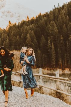 three women walking down a path with one carrying a child