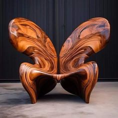 an unusual wooden chair sitting in front of a black wall