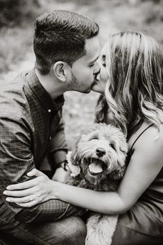 a man and woman kissing while holding a dog