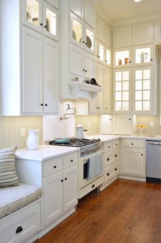 a kitchen with white cabinets and wood floors