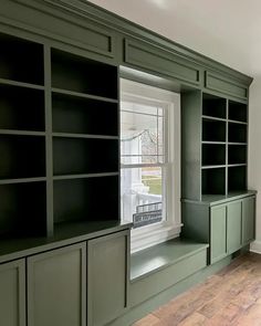 an empty room with built in bookshelves and cabinets on either side of the window