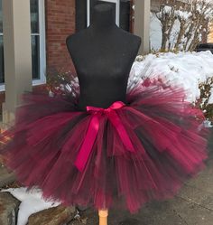 a mannequin wearing a red and black tutu with a pink bow on it