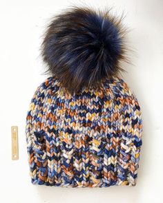 a multicolored knitted hat with a pom - pom on top