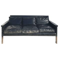 a black leather couch with wooden legs