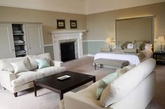 a living room filled with furniture and a fire place next to a white bed sitting on top of a hard wood floor