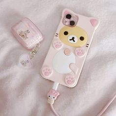 a pink phone case with a cat on it and a keychain next to it