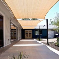 an outdoor patio with sun shade covering the walkway and door to the back yard area