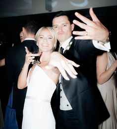 two people standing next to each other at a formal event with their arms in the air