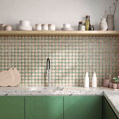 a kitchen with green cabinets and white dishes on the counter top, next to a wooden shelf